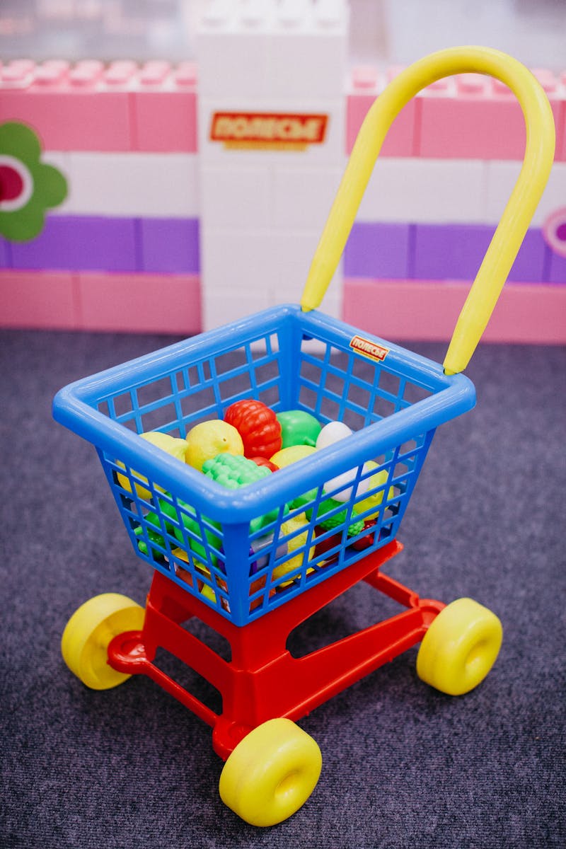 Bright toy cart filled with plastic fruits, ideal for pretend play and kids' activities.